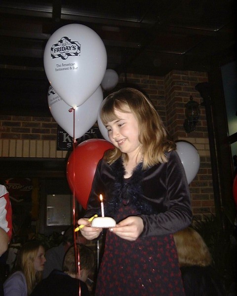9thBirthday3.jpg - 9th Birthday at TGIF standing on a chair to receive her cake